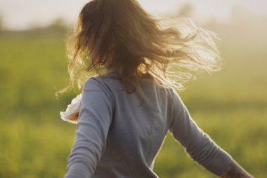 a woman in a field with her hair blowing in the wind